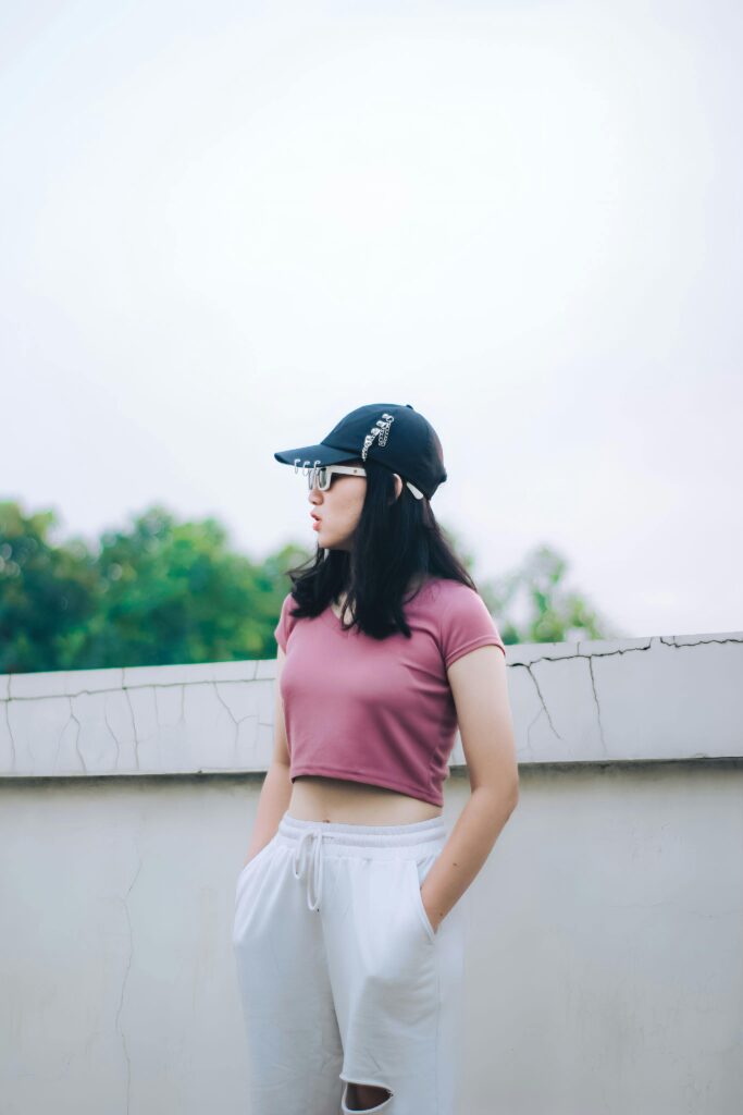 A woman in a pink crop top stands against a concrete wall outdoors in Cimahi, Indonesia.