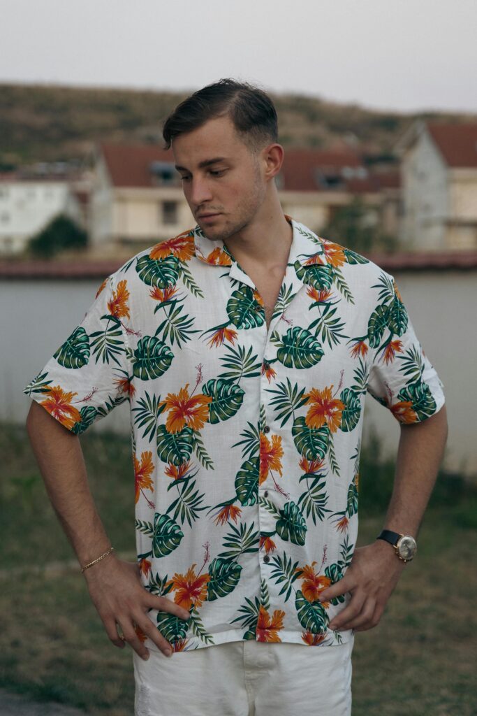 Man wearing a tropical floral shirt, standing outdoors during summer.